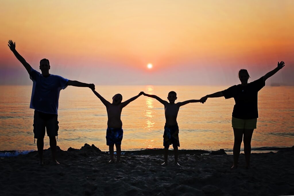 Family holding hands together on beach happy and smiling sunset after eating a meal and seeing dietitian.jpg